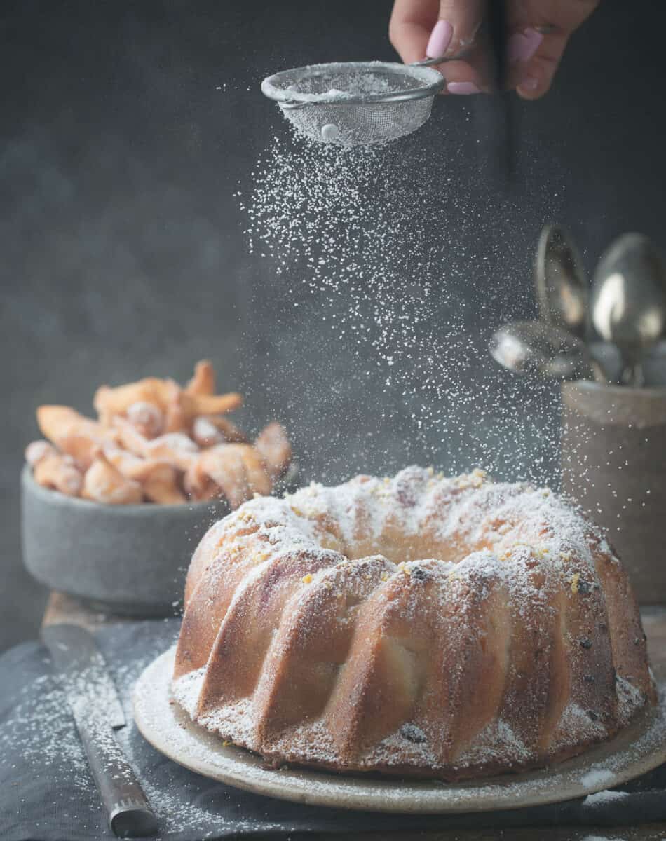 Rustic Style Apple Bundt Cake Sprinkled with Icing Sugar on old wooden table with woman hands.