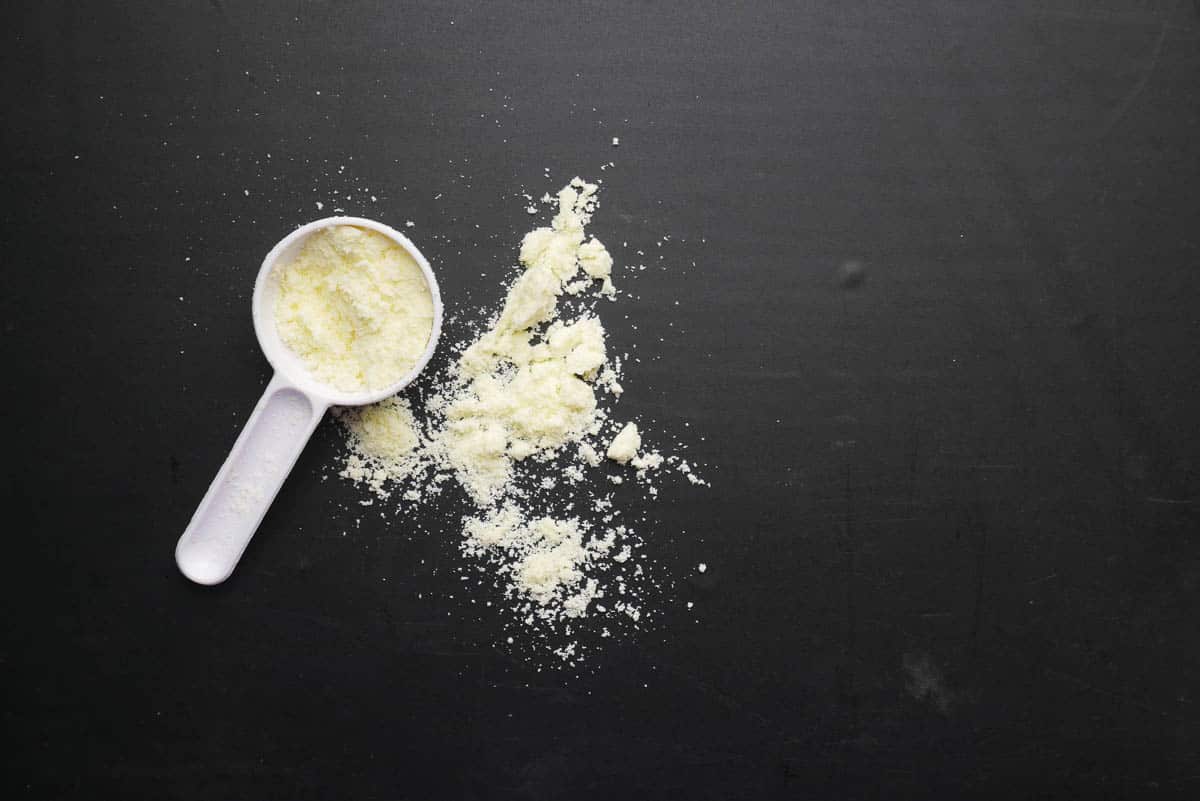 milk powder and spoon on black background.