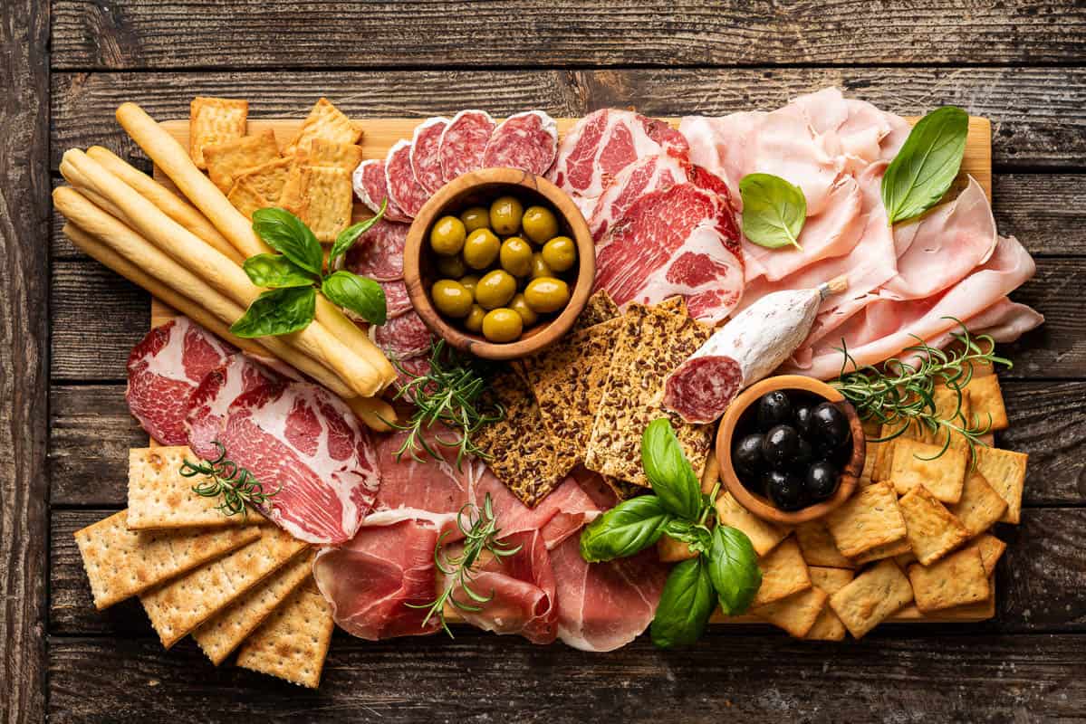 Appetizers with differents antipasti, charcuterie, snacks and red wine. Sausage, ham, tapas, olives and crackers for buffet party.