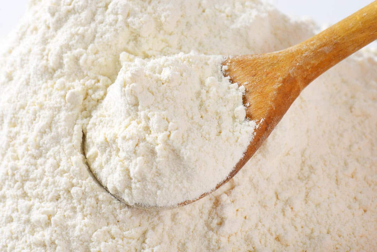 wooden spoon of wheat flour - close up.