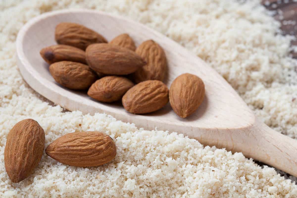 almond flour with almonds in a dark wood background.