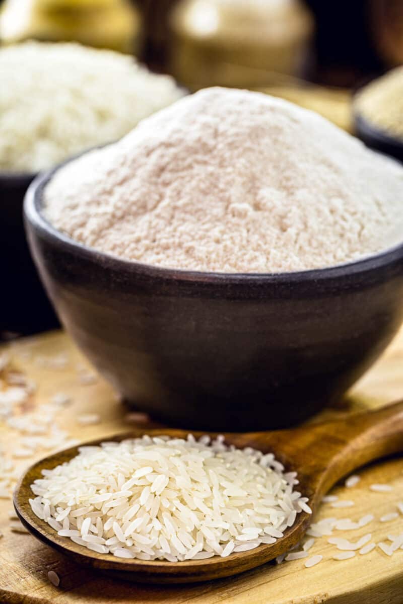 bowl of rice flour with spoonful of uncooked rice.