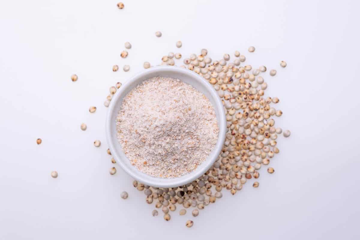 Uncooked raw Sorghum flour (also known as sorgo) in a white bowl, isolated on white background.
