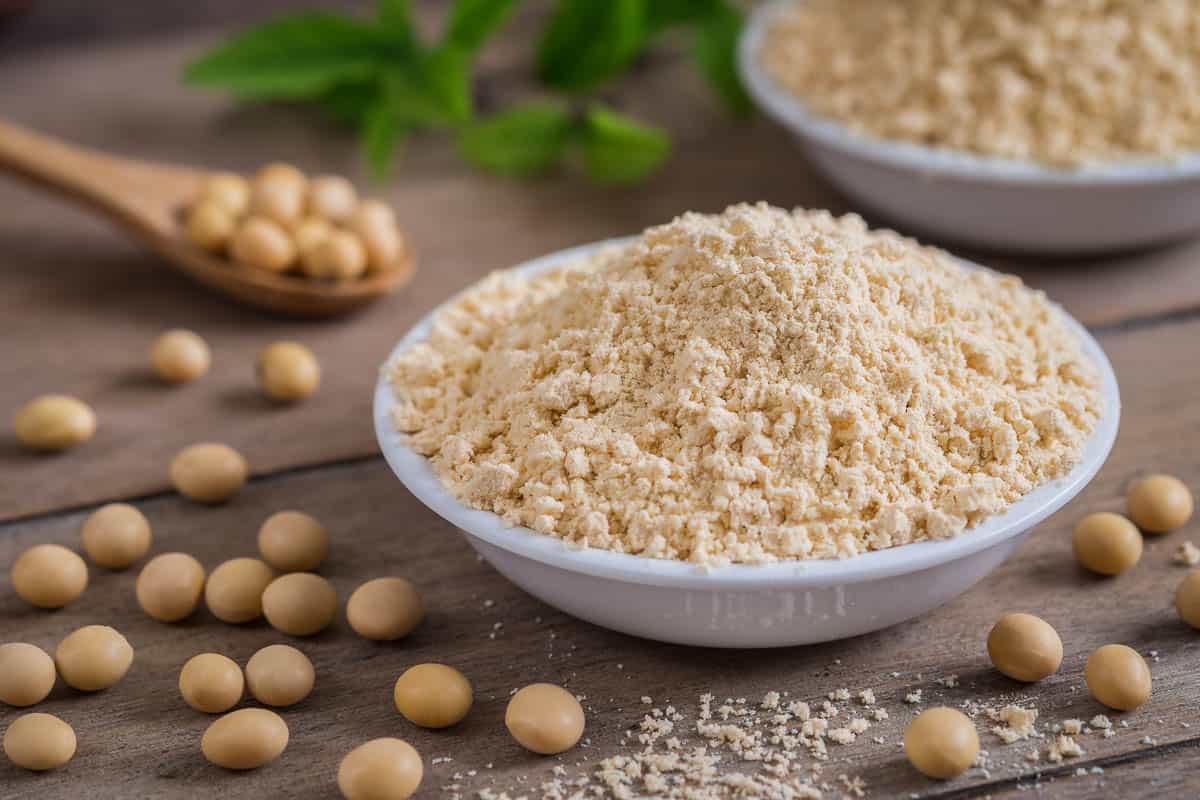 Soy flour in bowl and dried soybeans.