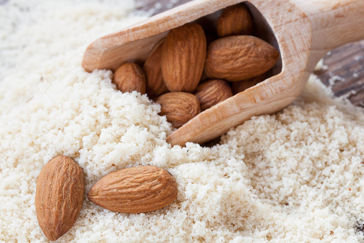 almond flour, almonds in a dark wood background.