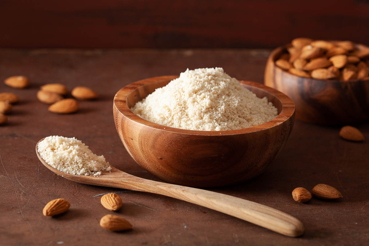 almond flour in a container with almond nut on table.