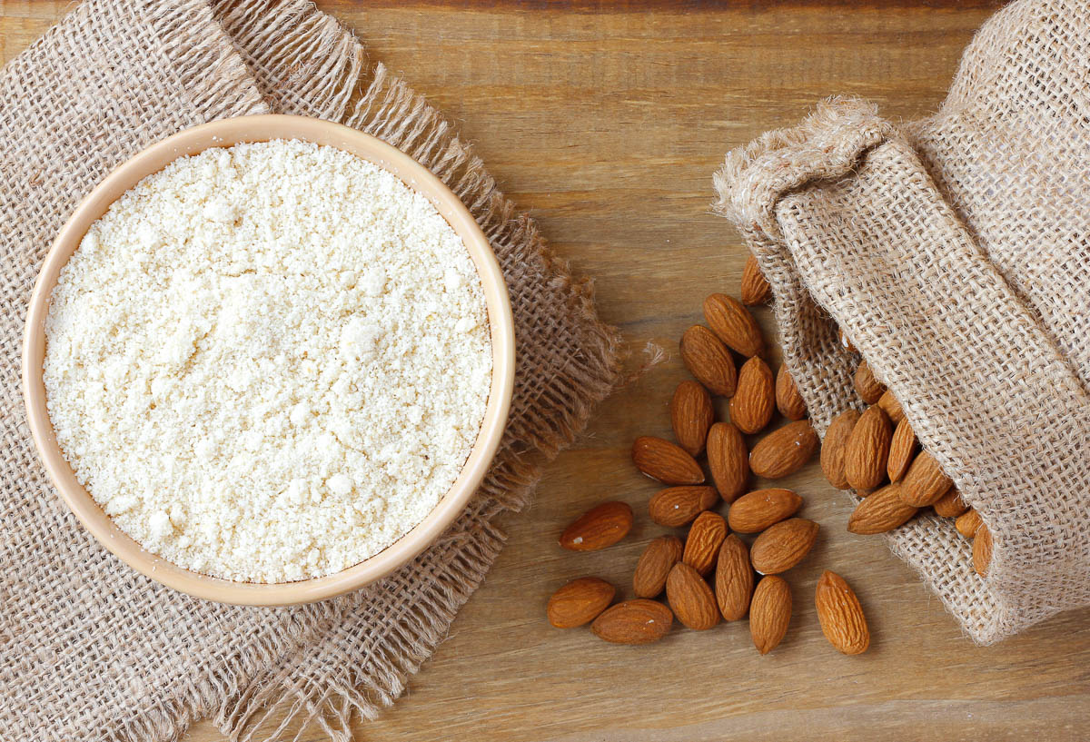 raw almond flour in bowl over rustic wooden table.