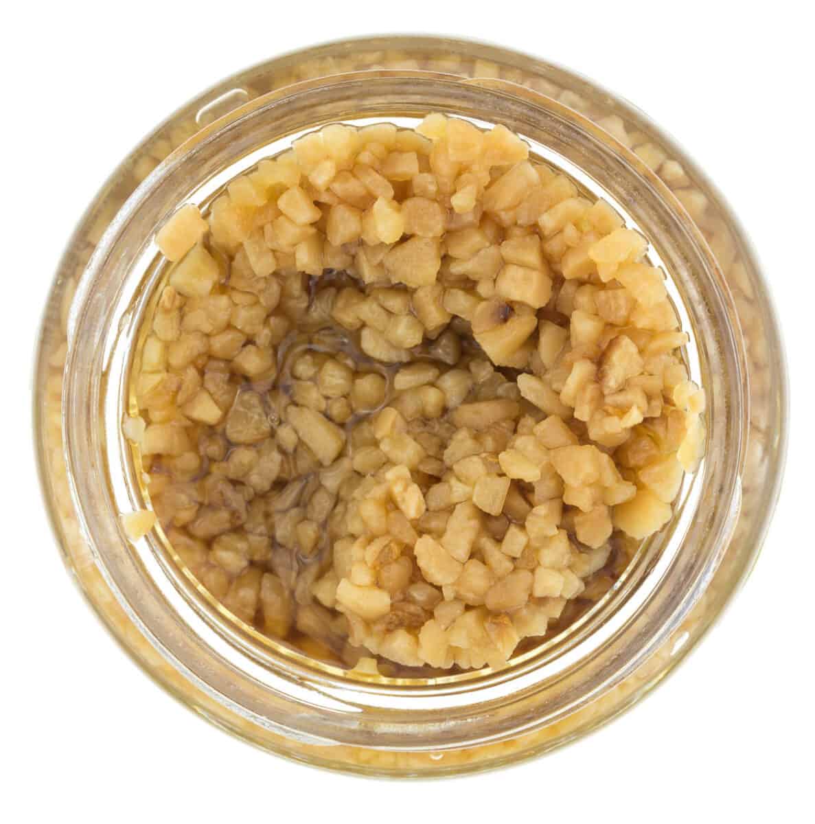 Top view of an opened jar of roasted minced garlic.