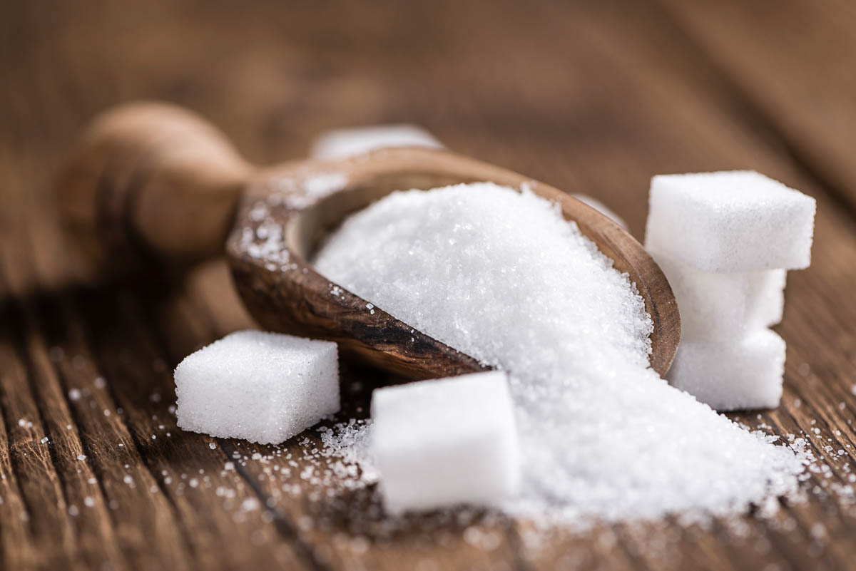 wooden scoop of granulated sugar with sugar cubes.