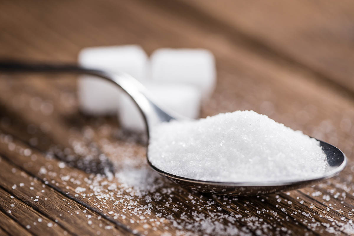 white sugar on spoon with sugar cubes in background.