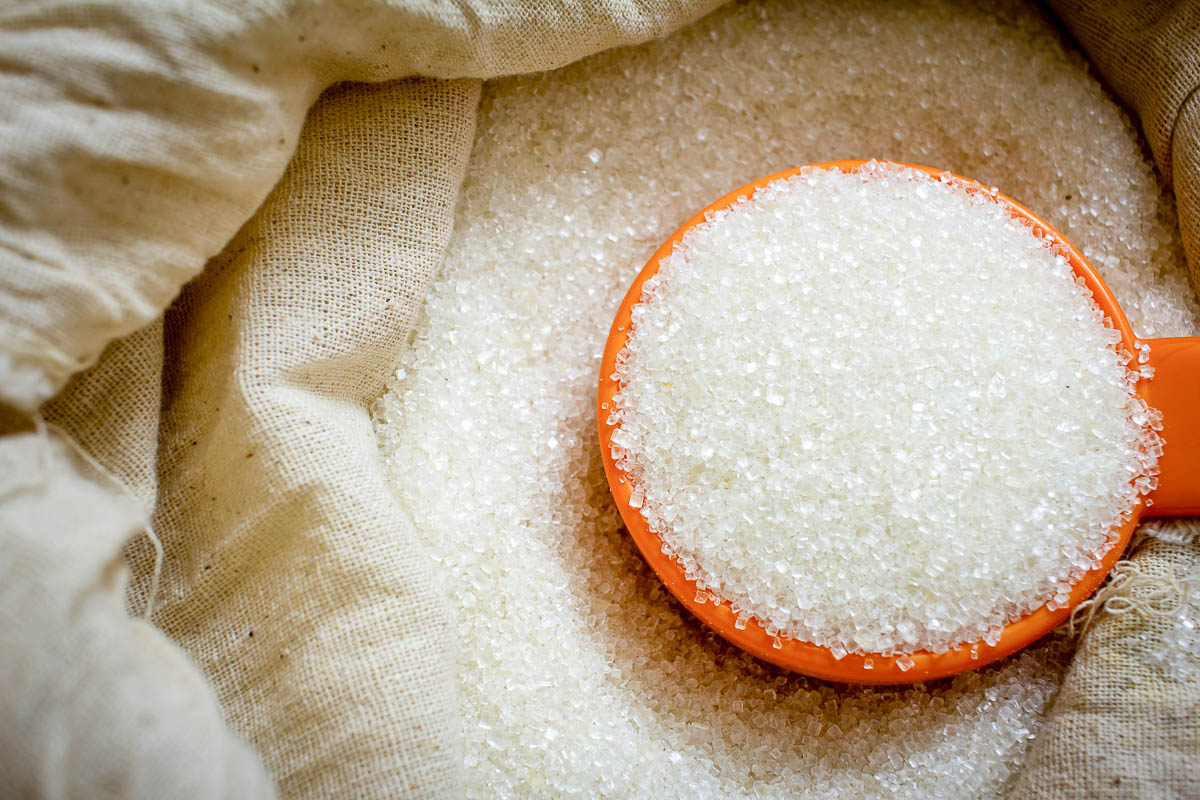 Granulated white cane sugar in a sack with a scoop.