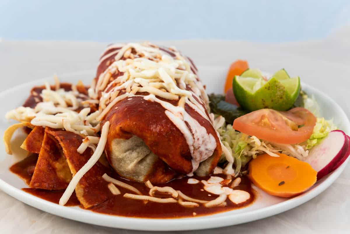 Wet ranchero burrito with rice and beans served on a hot plate.