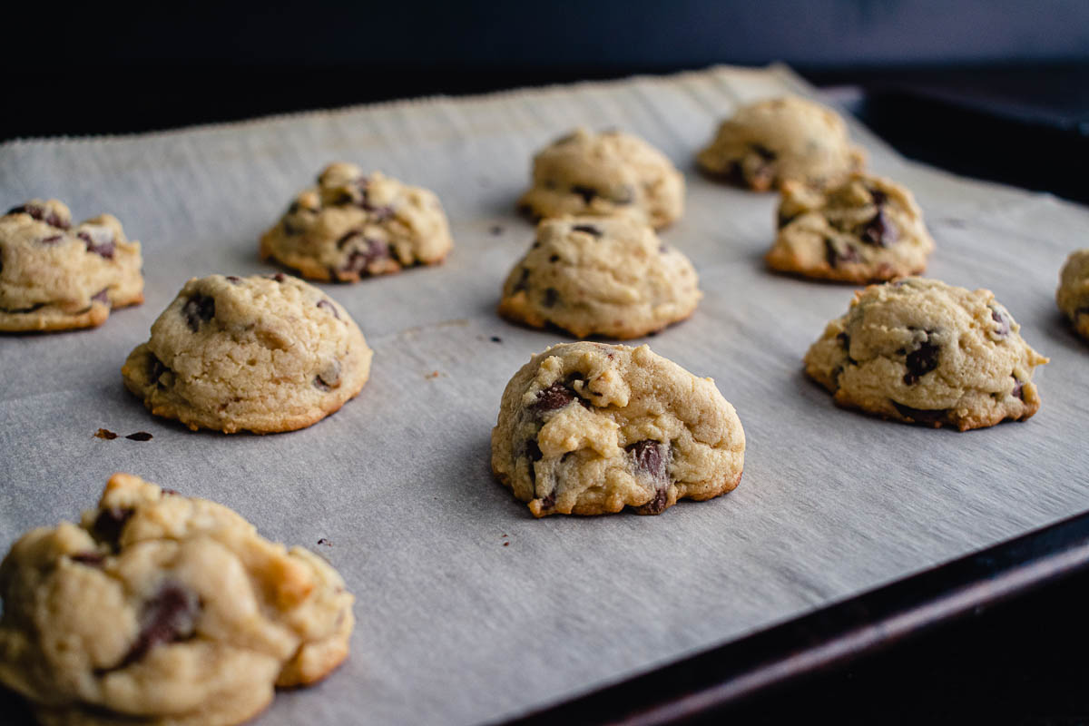 Chocolate chip cookies on a sheet pan lined with parchment paper.