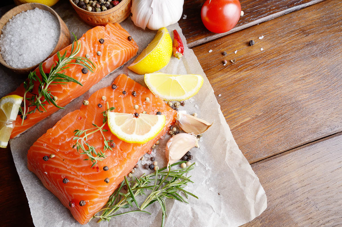 Raw salmon fillet with rosemary pepper sweetbread and salt on baking paper rustic theme.