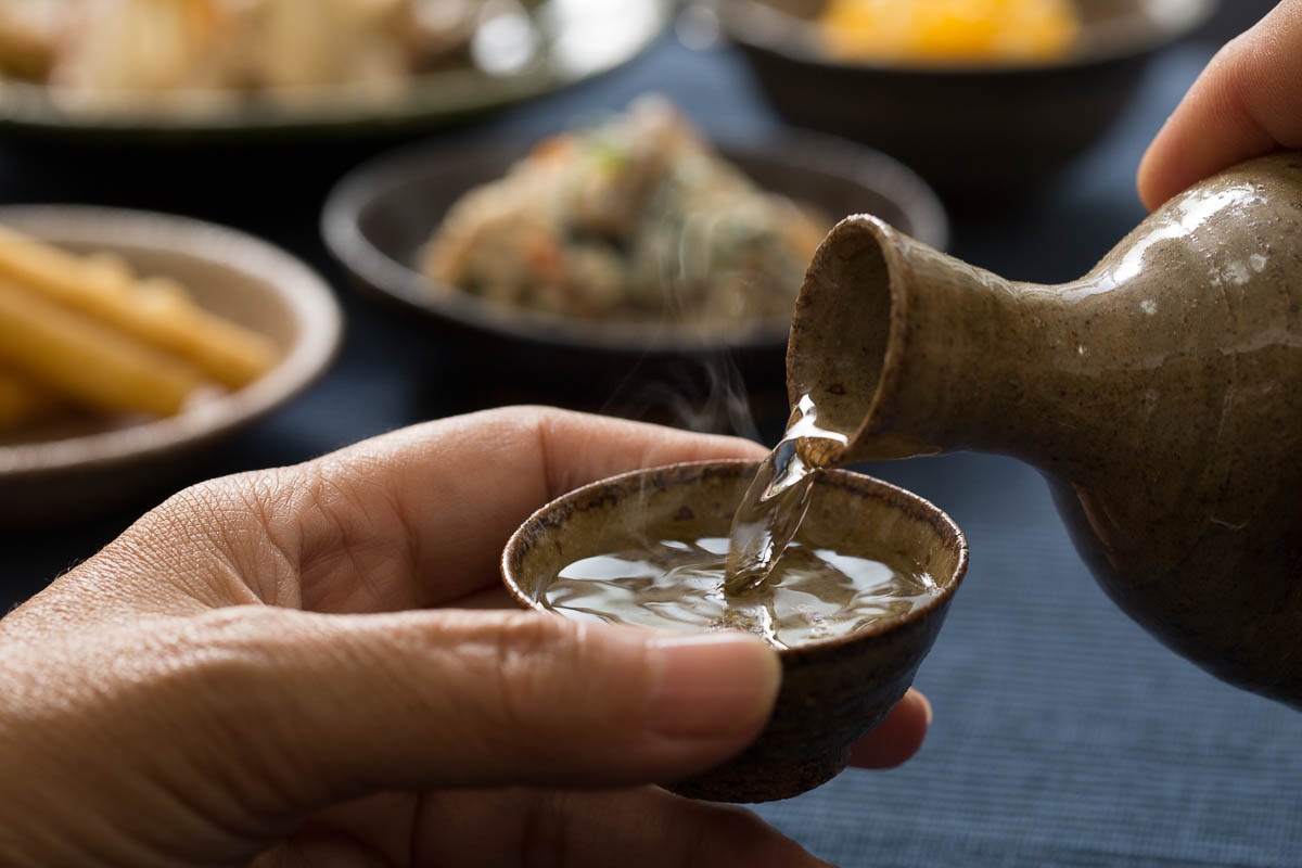 pouring hot Sake into small cup.