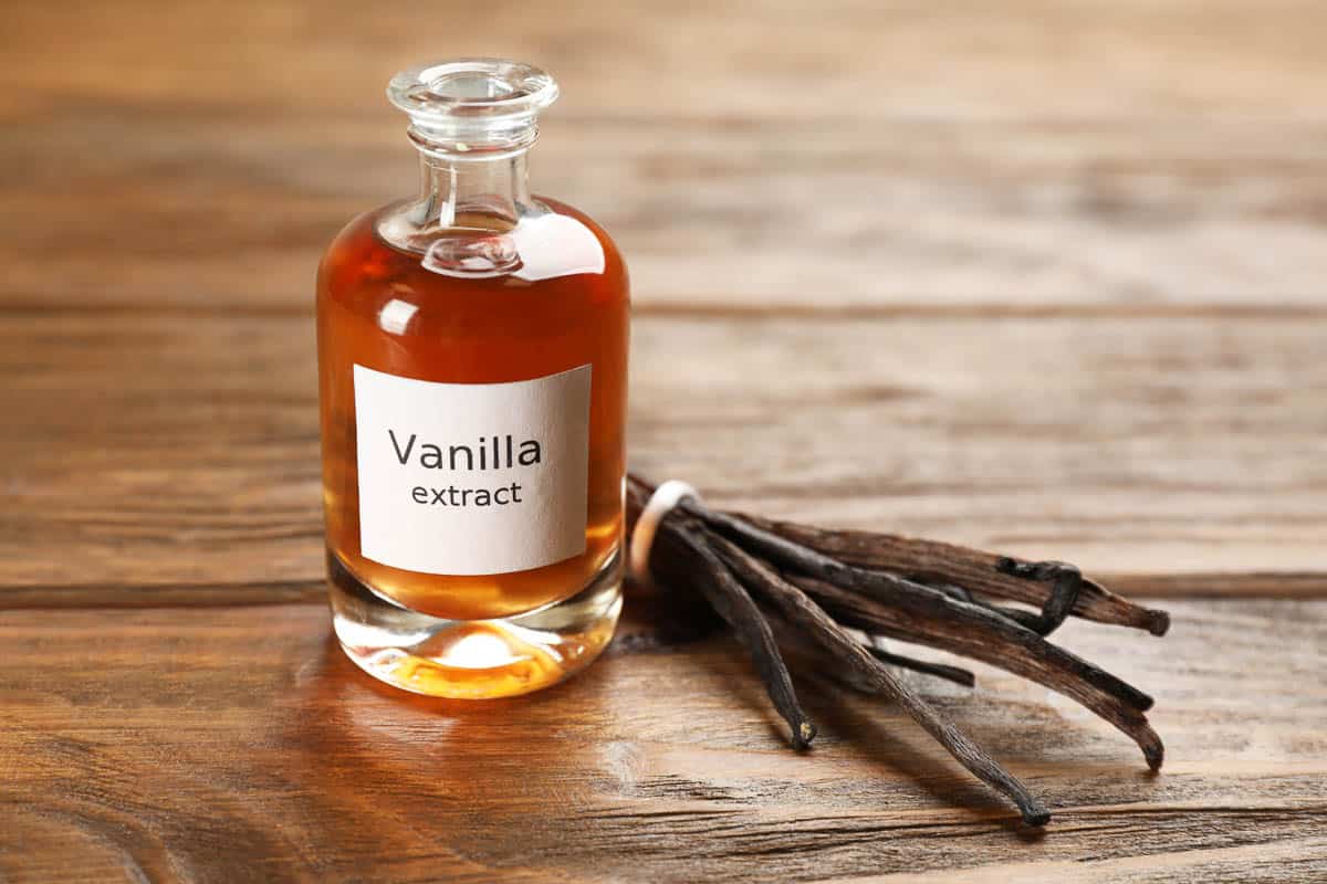 vanilla extract and beans on wooden table.