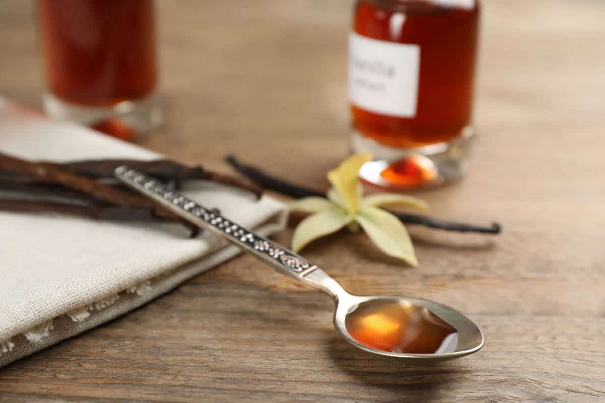 vanilla extract and dry pods on wooden table.