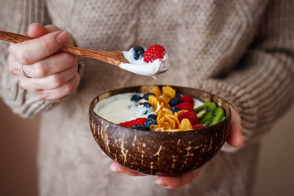 Woman eating healthy breakfast from coconut bowl.