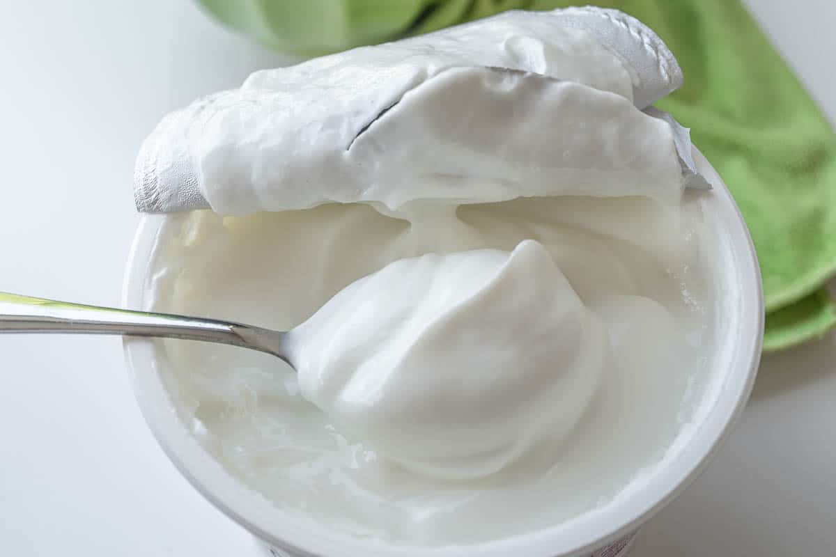 Scooping sour cream out of container.